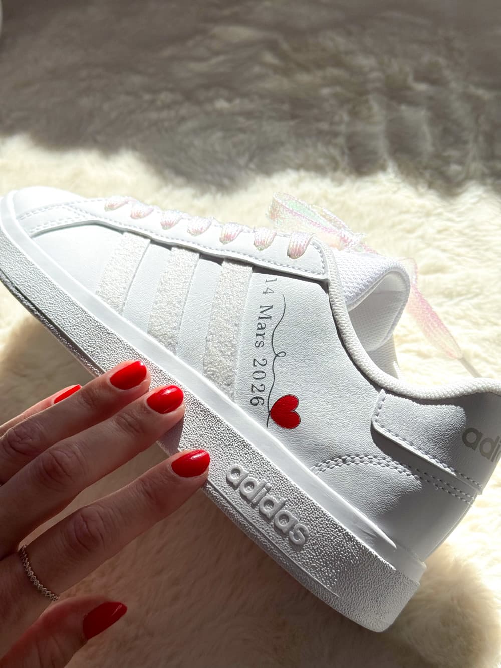 Baskets Adidas blanches personnalisées pour mariée avec lacets irisés et inscription personnalisée, sneakers de mariage élégantes.