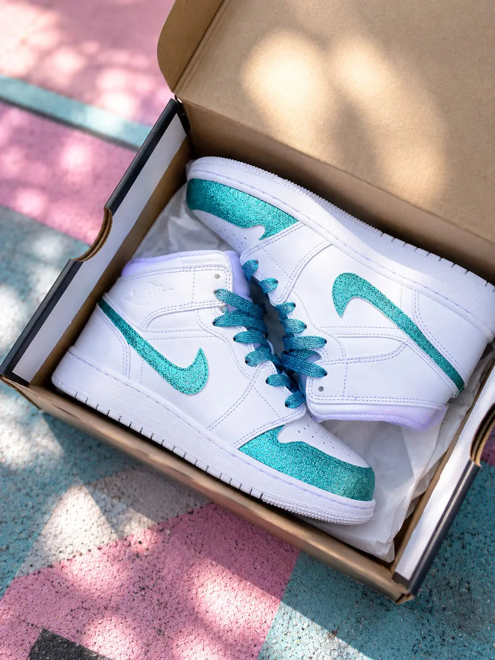 Paire de Nike Air Jordan 1 Mid custom turquoise glitter présentée dans sa boîte style sneakers premium femme