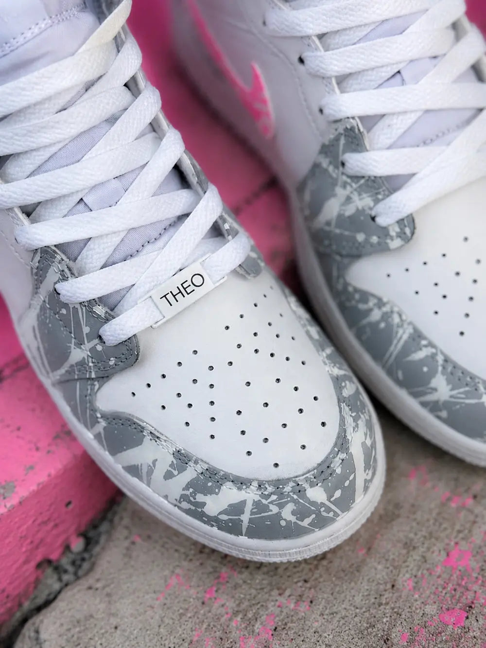 Détail d’une basket custom femme rose et grise avec finitions premium et design streetwear artistique.
