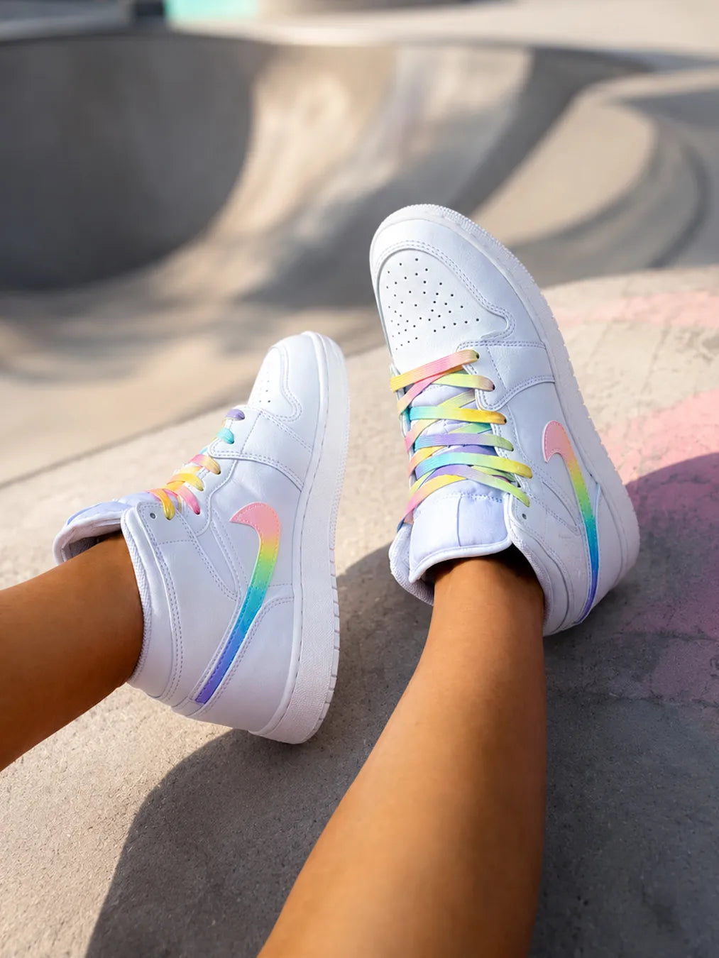 Air Jordan Mid personnalisée pastel portée en extérieur, basket custom femme aux finitions arc-en-ciel.