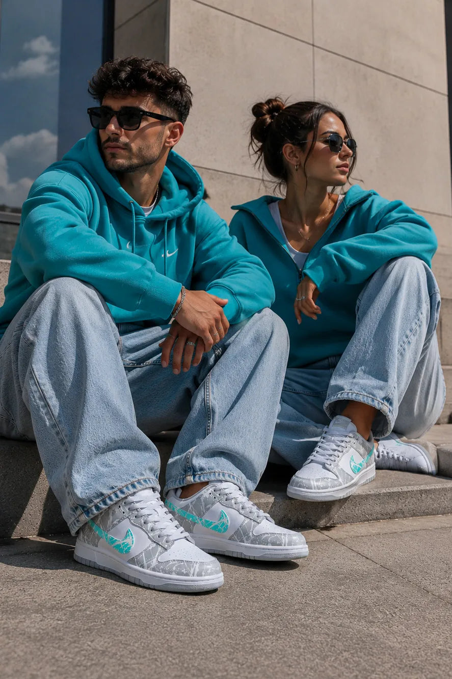 Couple portant des Nike Dunk custom gris et turquoise, baskets personnalisées artisanales au style streetwear.