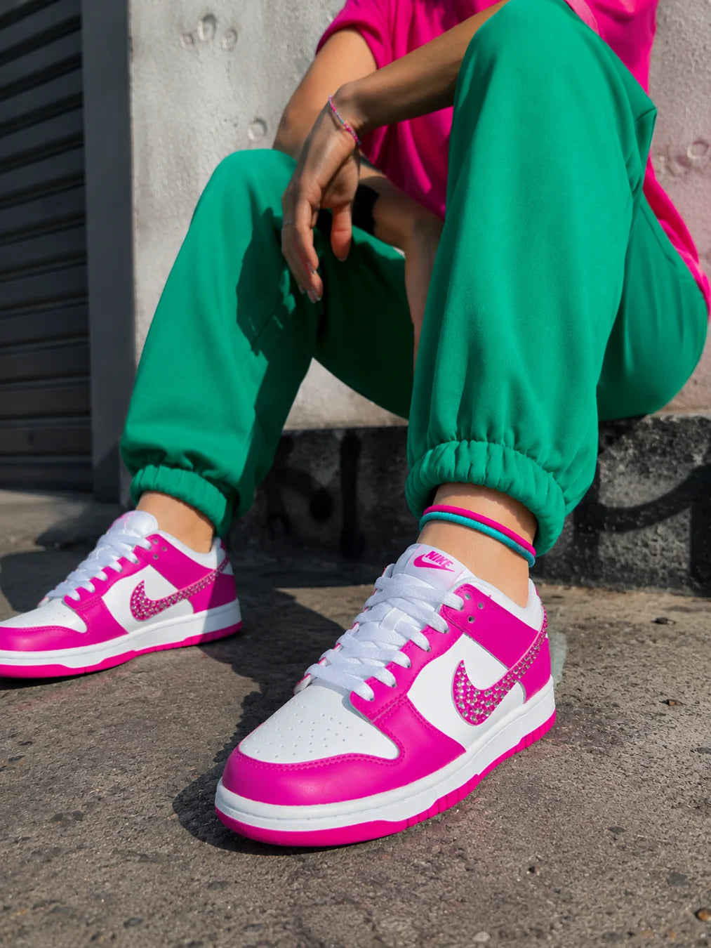 Basket femme personnalisée Nike Dunk Low rose fuchsia à strass portée dans un univers streetwear.