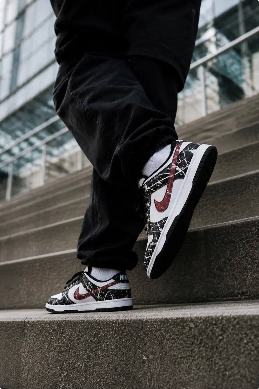 Nike Dunk Low custom noir et bordeaux style streetwear moderne avec motif abstrait blanc effet peinture et look urbain premium.