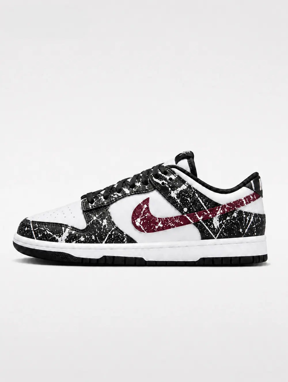 Paire de Nike Dunk Low custom noire et blanche avec swoosh bordeaux et motif paint splatter artisanal haut de gamme.