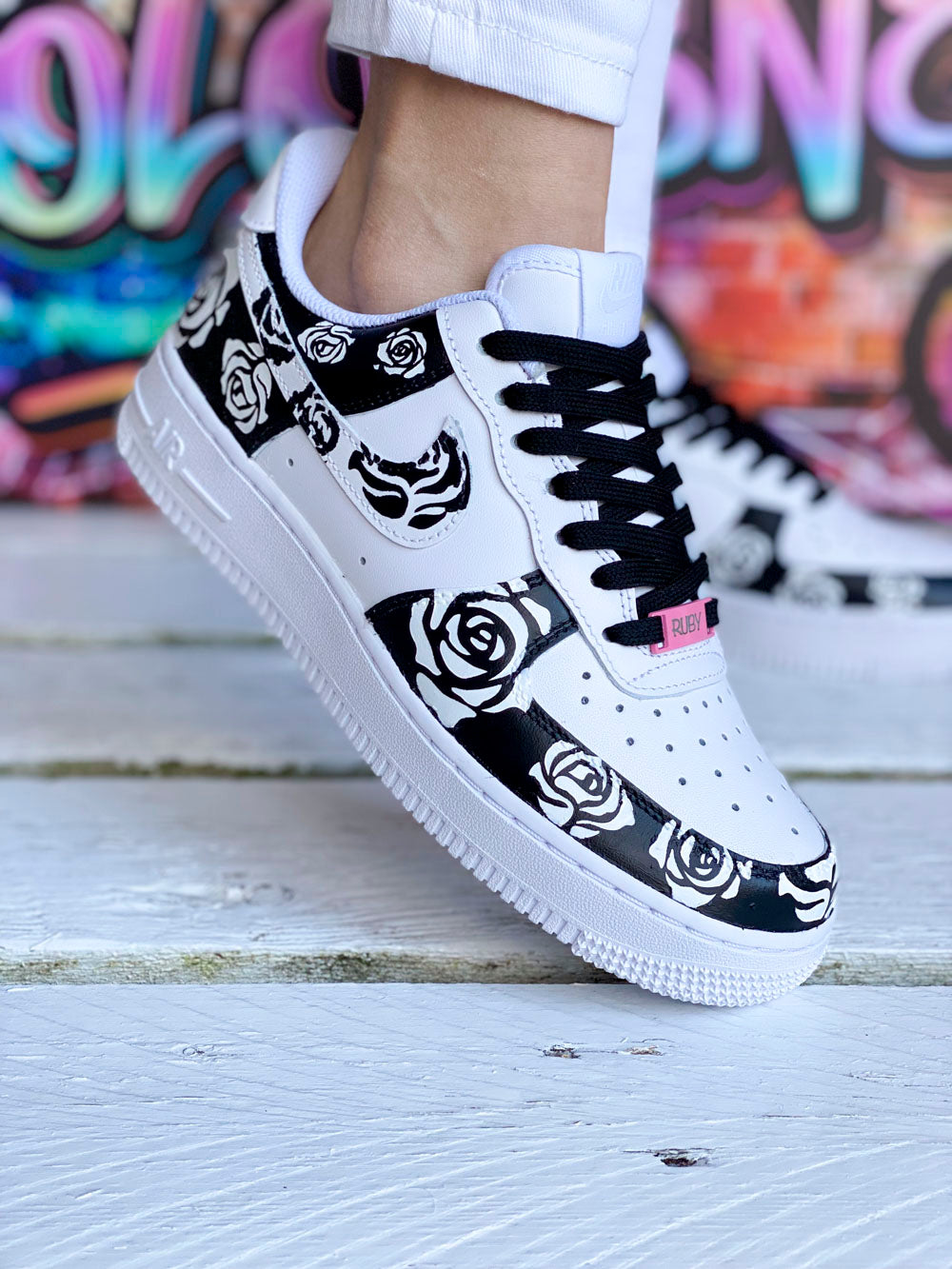 Sur la photo, des baskets Nike Air Force 1 avec un contraste noir et blanc pour un rendu moderne et raffiné.