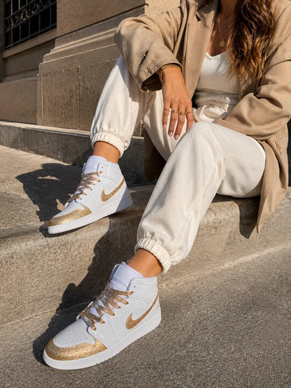 Nike Air Jordan blanche et or glitter portée dans un look chic casual avec bijoux dorés et tenue élégante