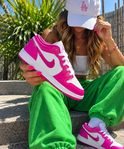Femme présentant une Air Jordan personnalisée rose fuchsia avec swoosh en strass.