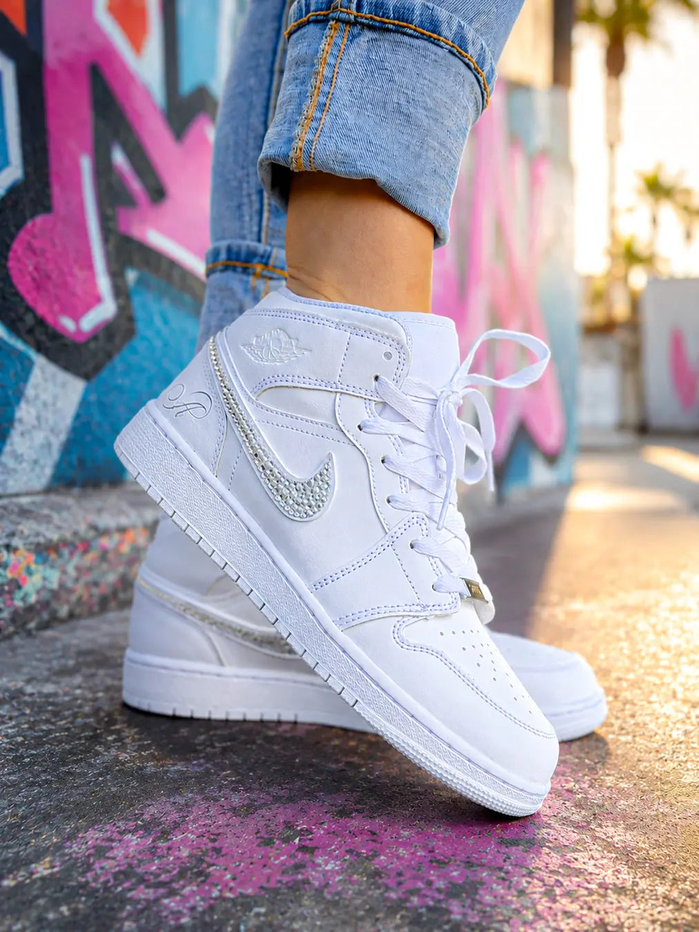 Air Jordan Mid blanche pour femme personnalisée avec un swoosh recouvert de strass argentés.