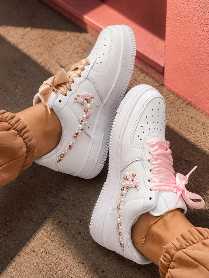 Baskets custom femme style streetwear chic avec perles roses, détails dorés et lacets satin sur Nike Air Force 1 blanche
