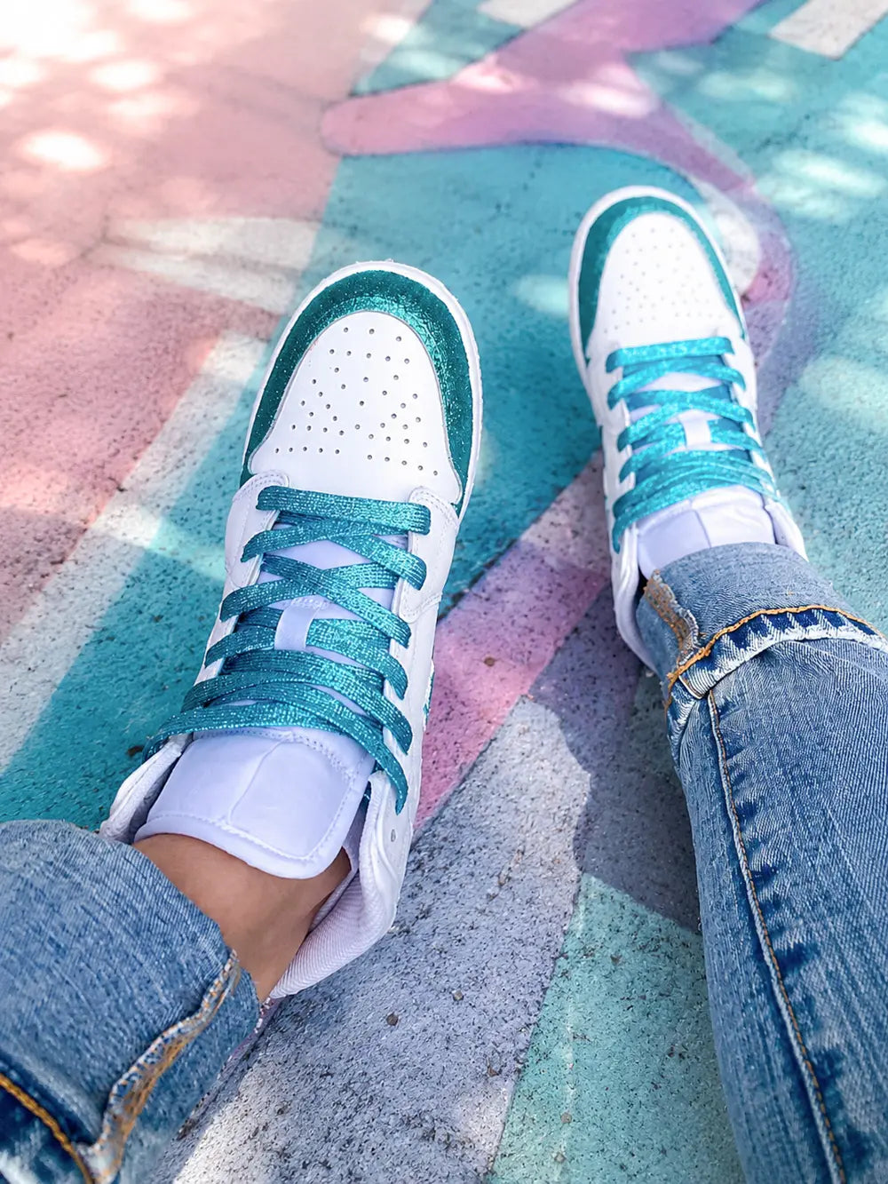 Nike Air Jordan 1 Mid blanche personnalisée glitter turquoise portée par une femme en tenue streetwear avec lacets turquoise brillants