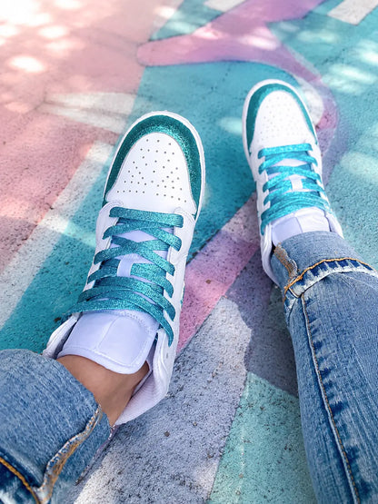 Nike Air Jordan 1 Mid blanche personnalisée glitter turquoise portée par une femme en tenue streetwear avec lacets turquoise brillants