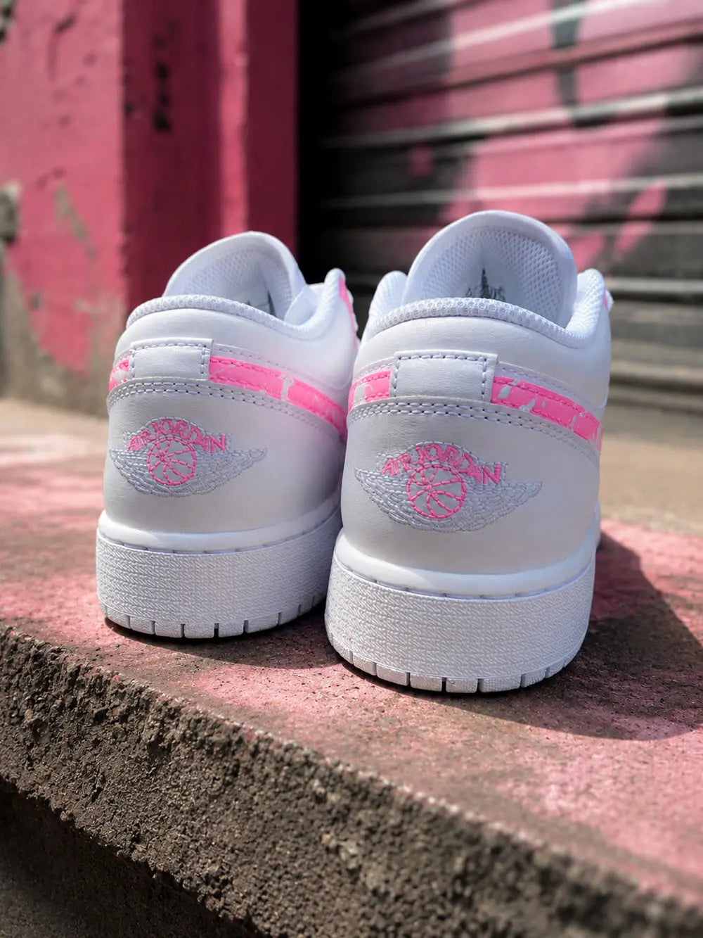 Basket Jordan Low custom rose fluo pour femme dans un décor urbain streetwear moderne et tendance.