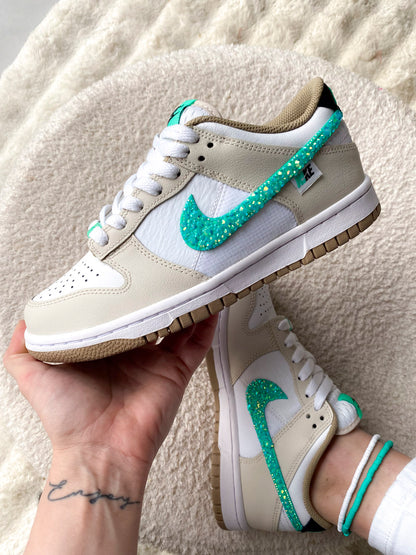 Voici une paire de Nike Dunk Low pour femme, dans un mélange élégant de beige et turquoise avec des strass pour une touche de brillance