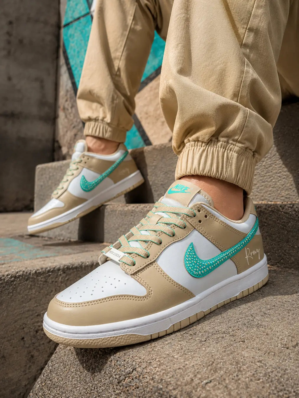 Basket Nike Dunk Low beige sable personnalisée avec prénom et swoosh turquoise à strass.