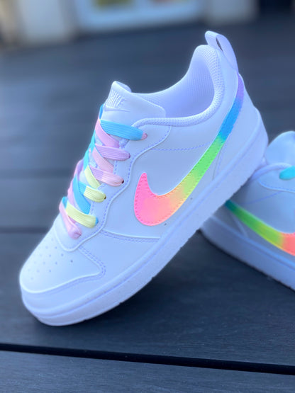 Sur la photo, une paire de baskets Nike avec un design arc-en-ciel fluo pour un look audacieux et coloré.