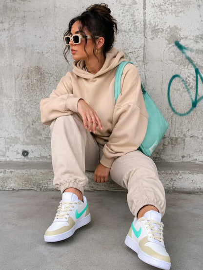 Femme portant des baskets Nike personnalisées beige et turquoise peintes à la main, modèle exclusif ColorSneak fabriqué en France.