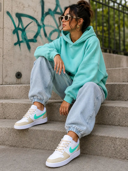 Sneakers Nike femme beige et turquoise personnalisées portées dans un style urbain moderne.