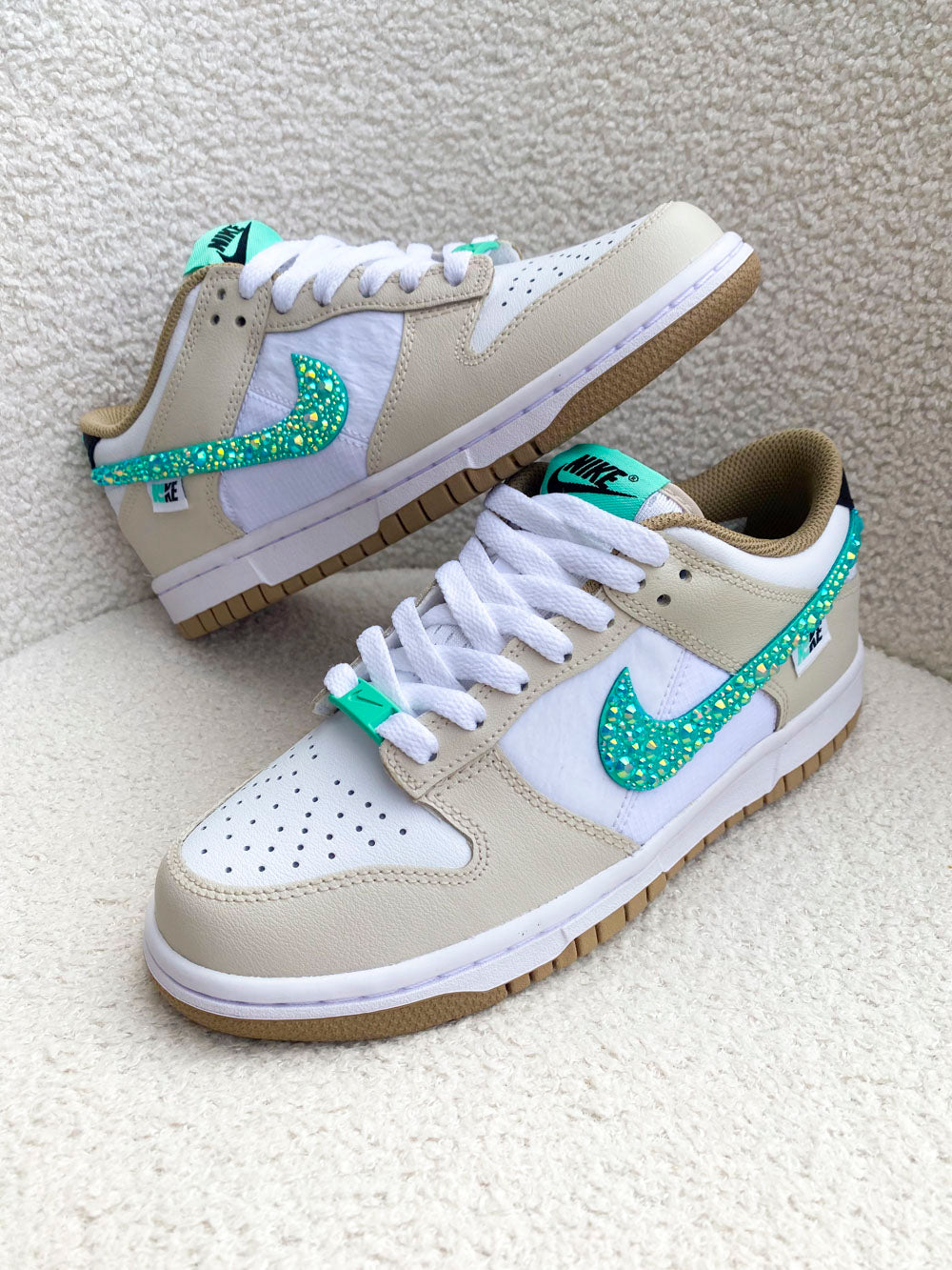 Une paire de Nike Dunk Low femme, beige et turquoise, personnalisée avec des strass pour un look unique et lumineux