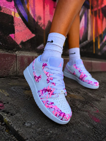 Air Jordan Low blanche custom rose fuchsia fluorescente portée en extérieur urbain, basket femme personnalisée style mode streetwear premium.