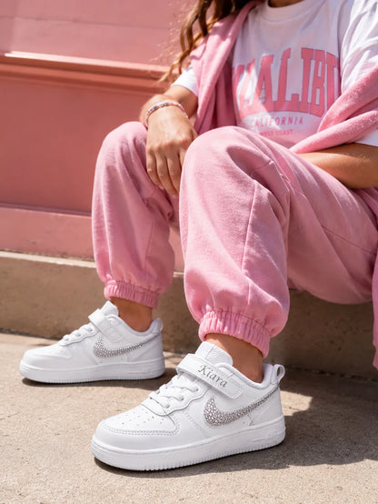 Basket Nike enfant personnalisée avec strass argent portée avec une tenue rose tendance pour un look mode et moderne.