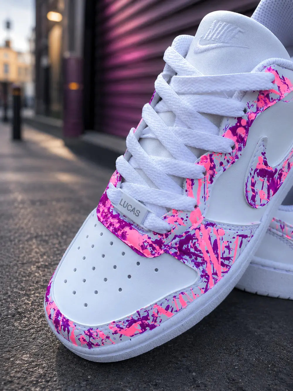 Gros plan Nike custom femme rose fuchsia avec lacets blancs et bijou chaussure personnalisé, basket tendance artisanale premium.