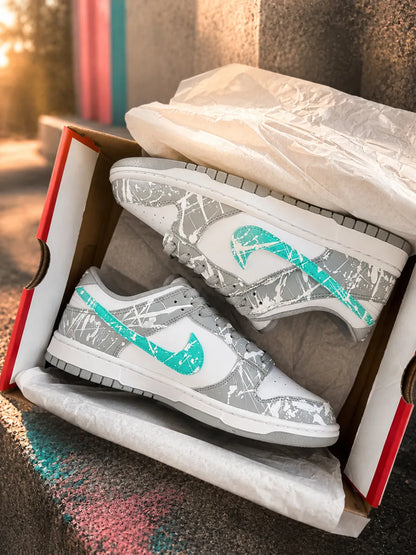 Paire de Nike Dunk personnalisées gris et turquoise présentée dans son coffret, création artisanale premium.