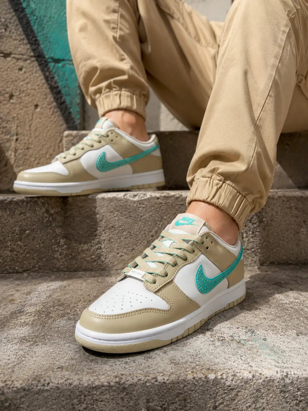 Nike Dunk Low personnalisée beige sable portée avec personnalisation artisanale et swoosh turquoise.