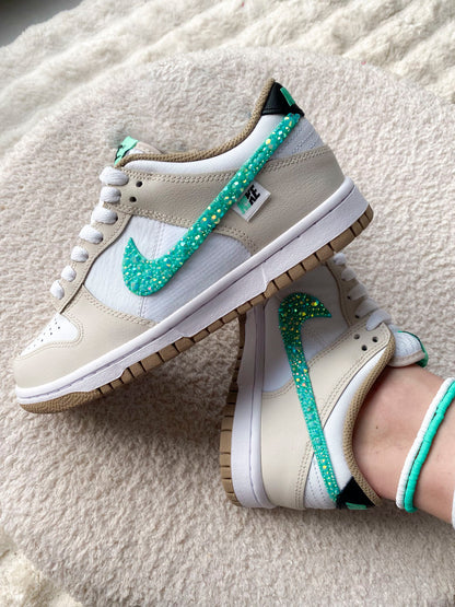 Sur la photo, des Nike Dunk Low femme avec une association de beige et turquoise, ornées de strass pour un style raffiné